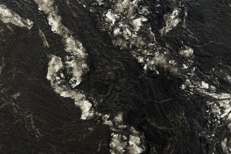Near-black rough-textured slab with wide white and pink crystalline seams running vertically