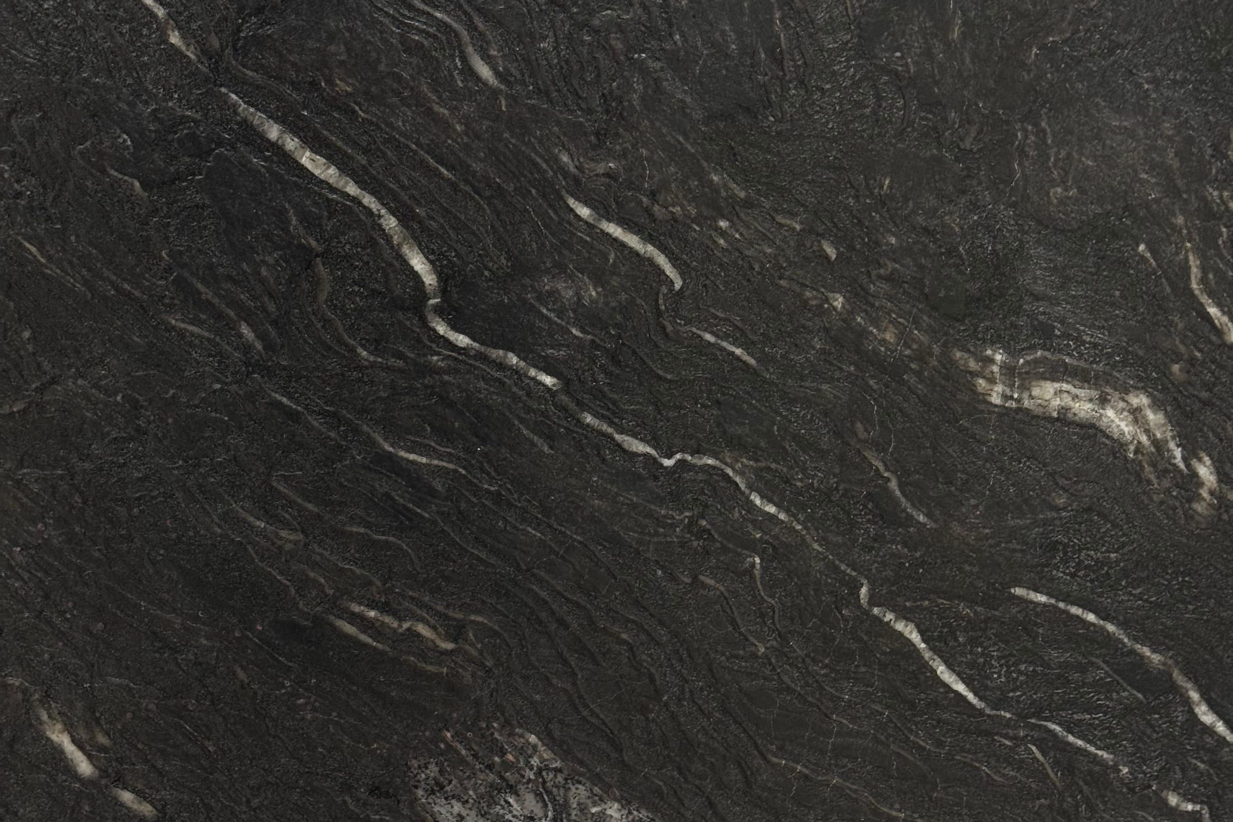 Near-black textured slab with thin cream streaks running diagonally across a rippled surface