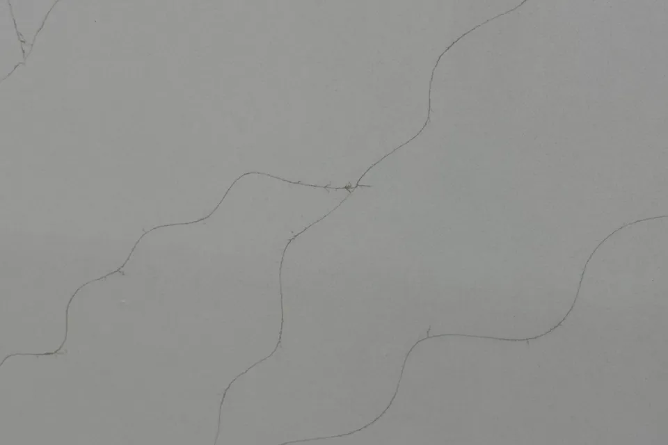 Mid gray slab with thin dark wavy lines running diagonally across a smooth surface