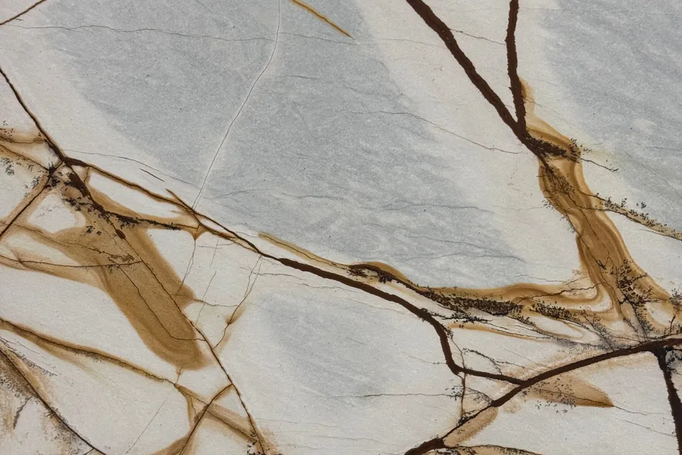 Cream and pale blue-gray stone crossed by wide dark brown and ochre veins