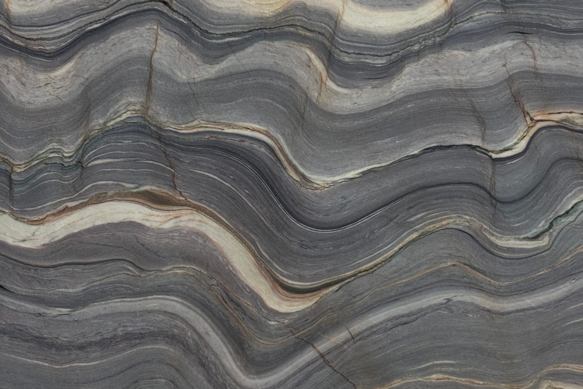 Folded gray bands with cream and mauve stripes rippling across the slab