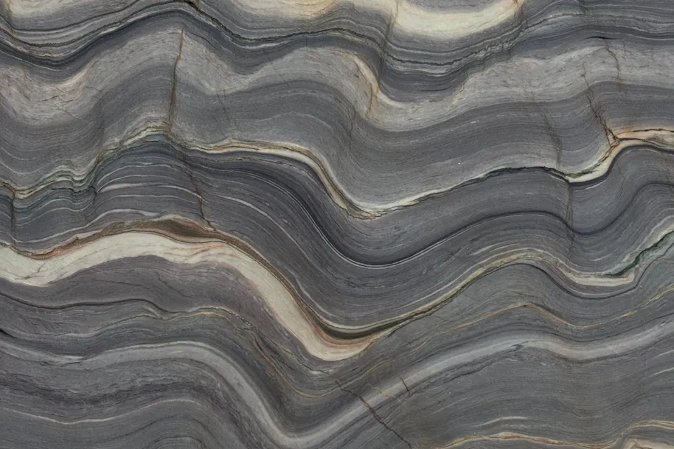 Folded gray bands with cream and mauve stripes rippling across the slab