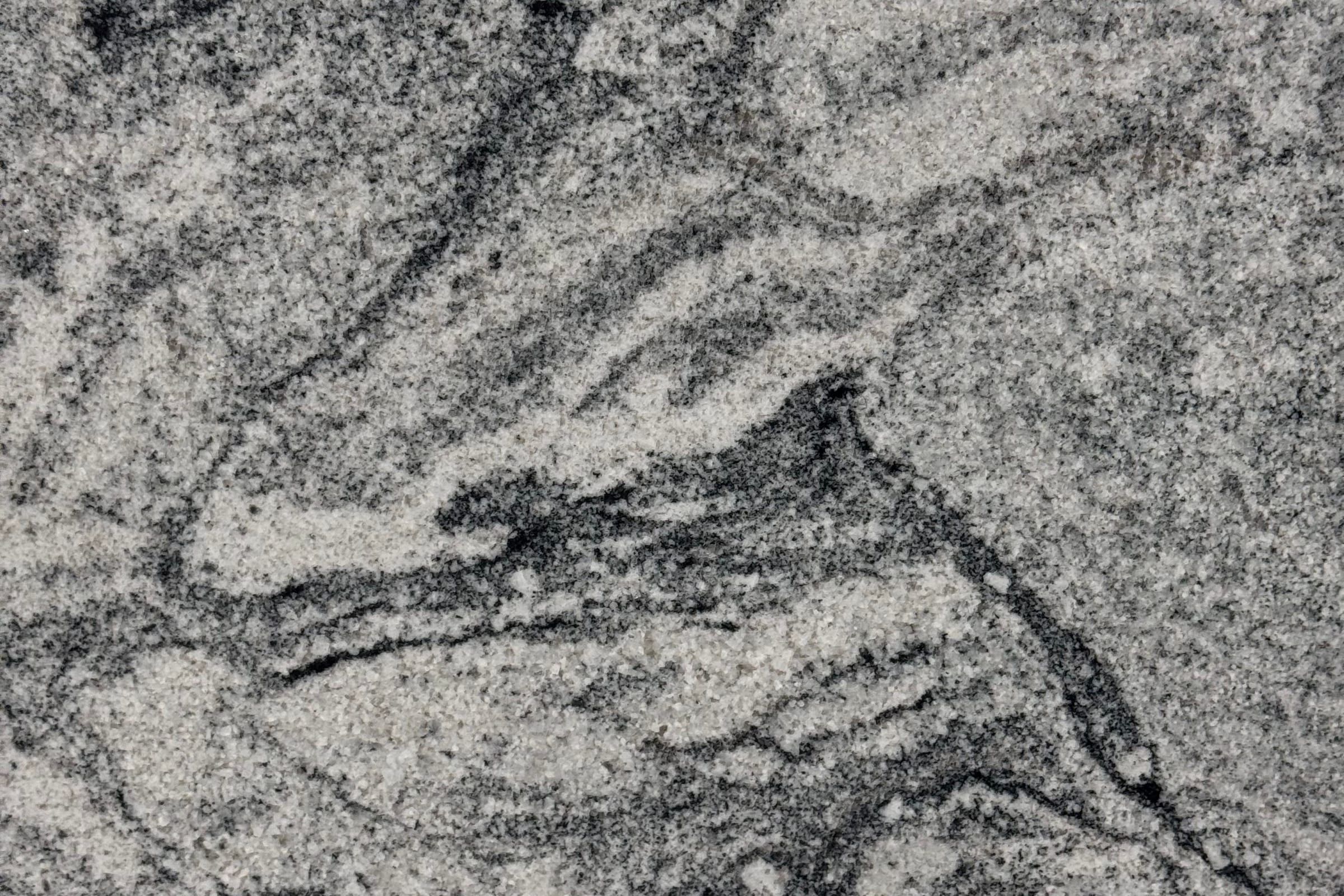 Light gray granular slab with darker gray and black swirls flowing in curved bands