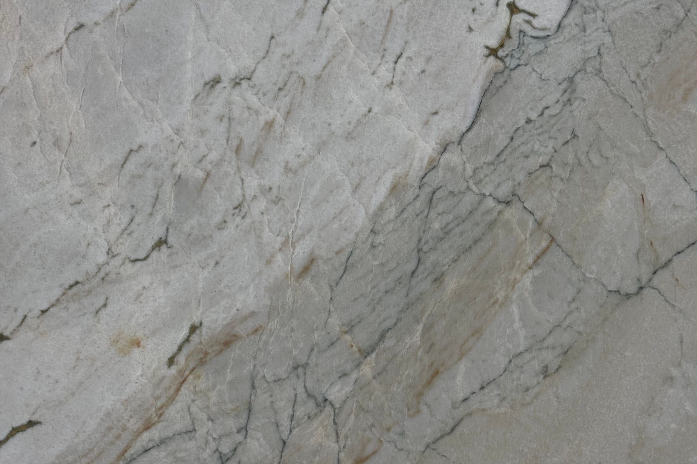 Pale gray stone with fine dark crackle lines, rust stains and a darker diagonal band