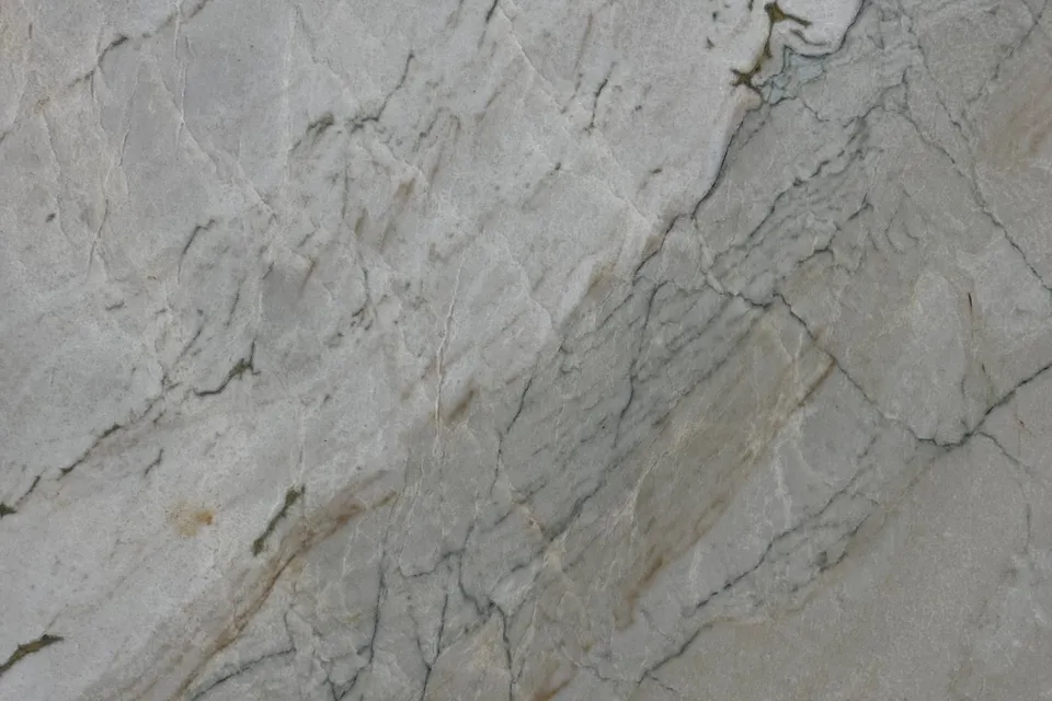Pale gray stone with fine dark crackle lines, rust stains and a darker diagonal band