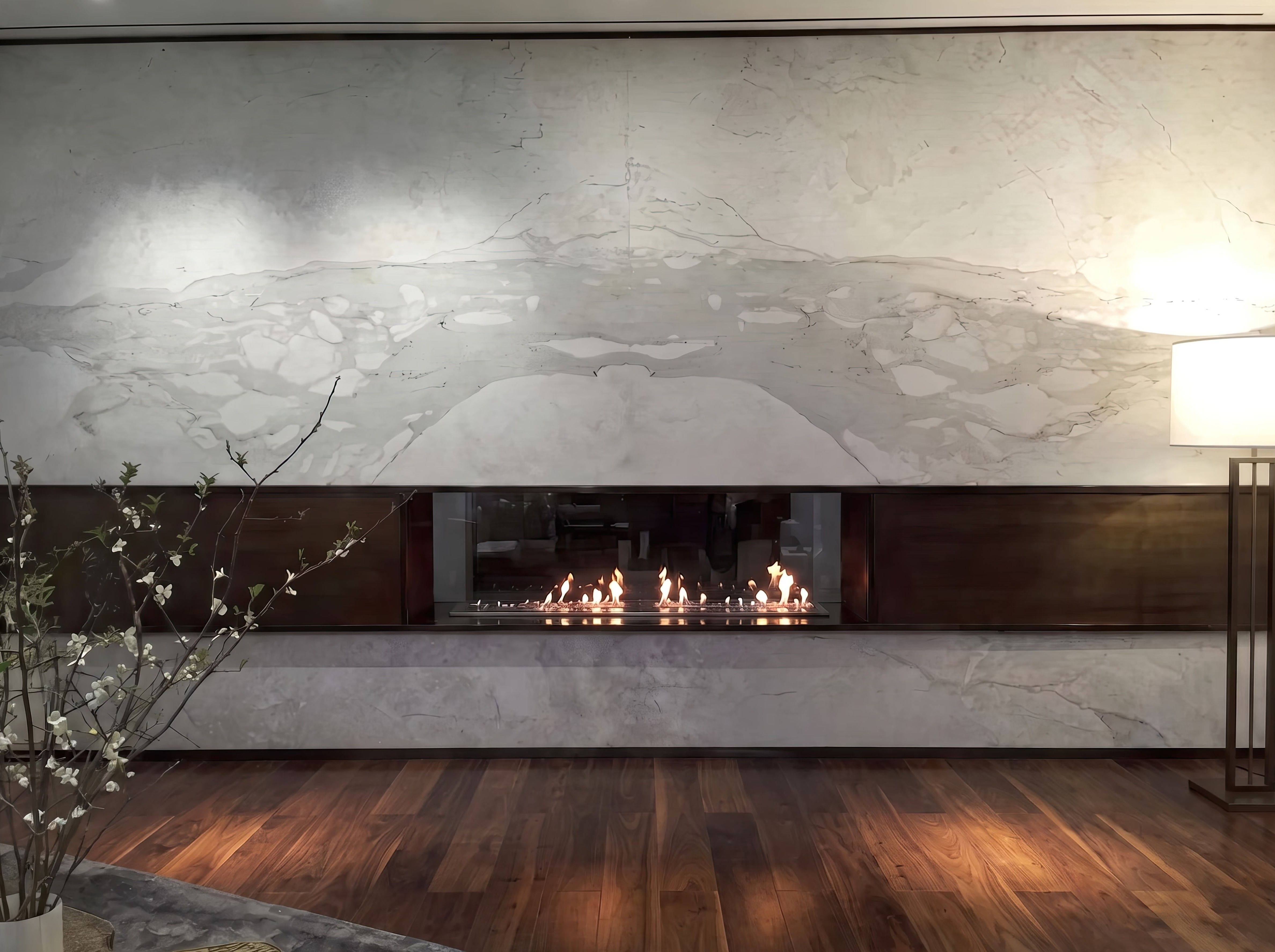 Book-matched white marble wall around a linear fireplace, the veining mirrored across the seam