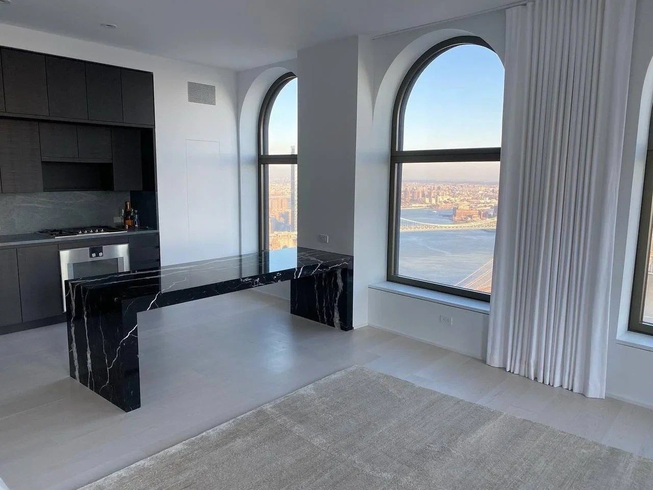 Nero Marquina marble desk with mitered waterfall legs in an apartment with arched windows