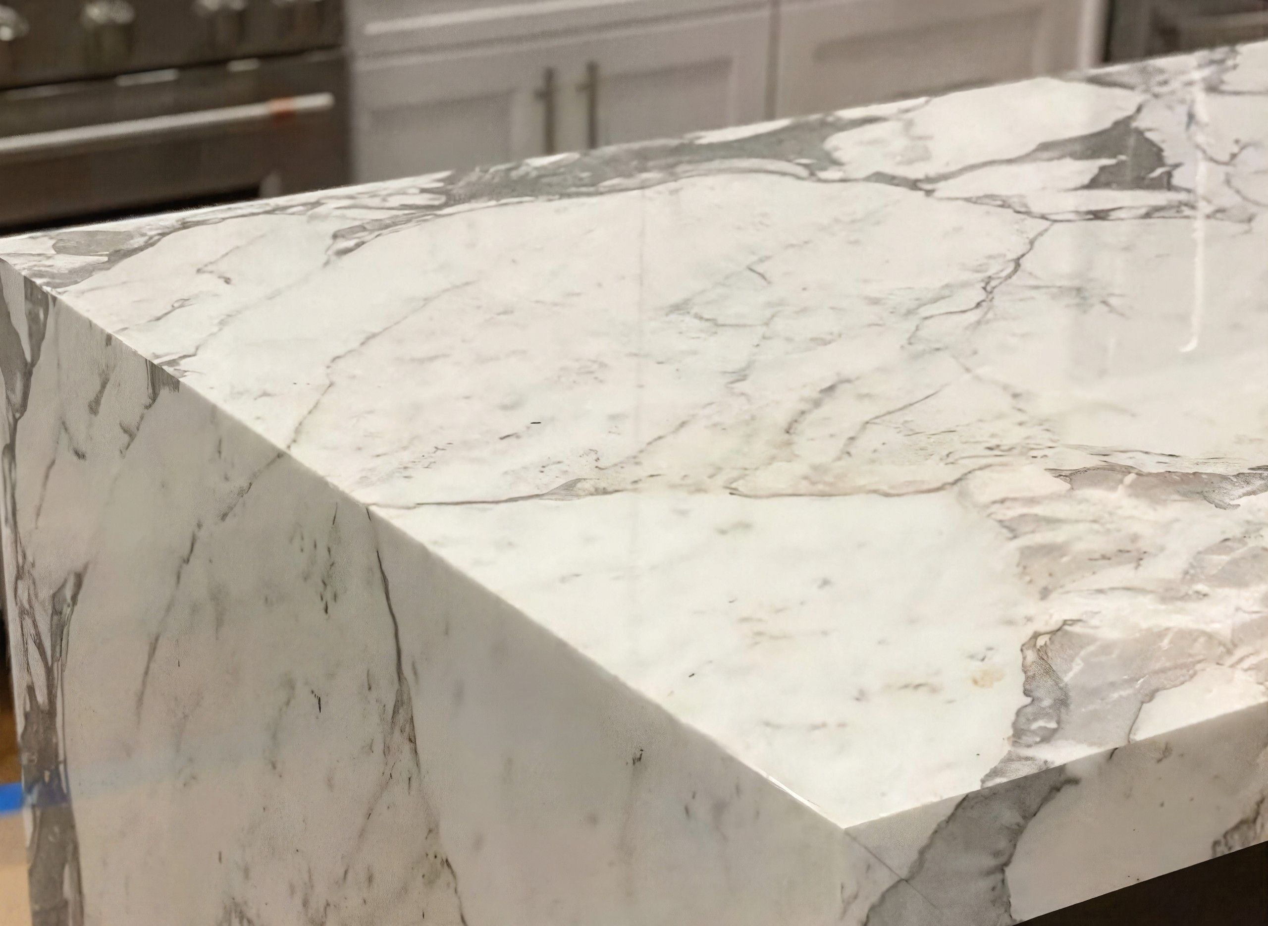 Stepped white marble bath surround, each course mitered at the inside corner