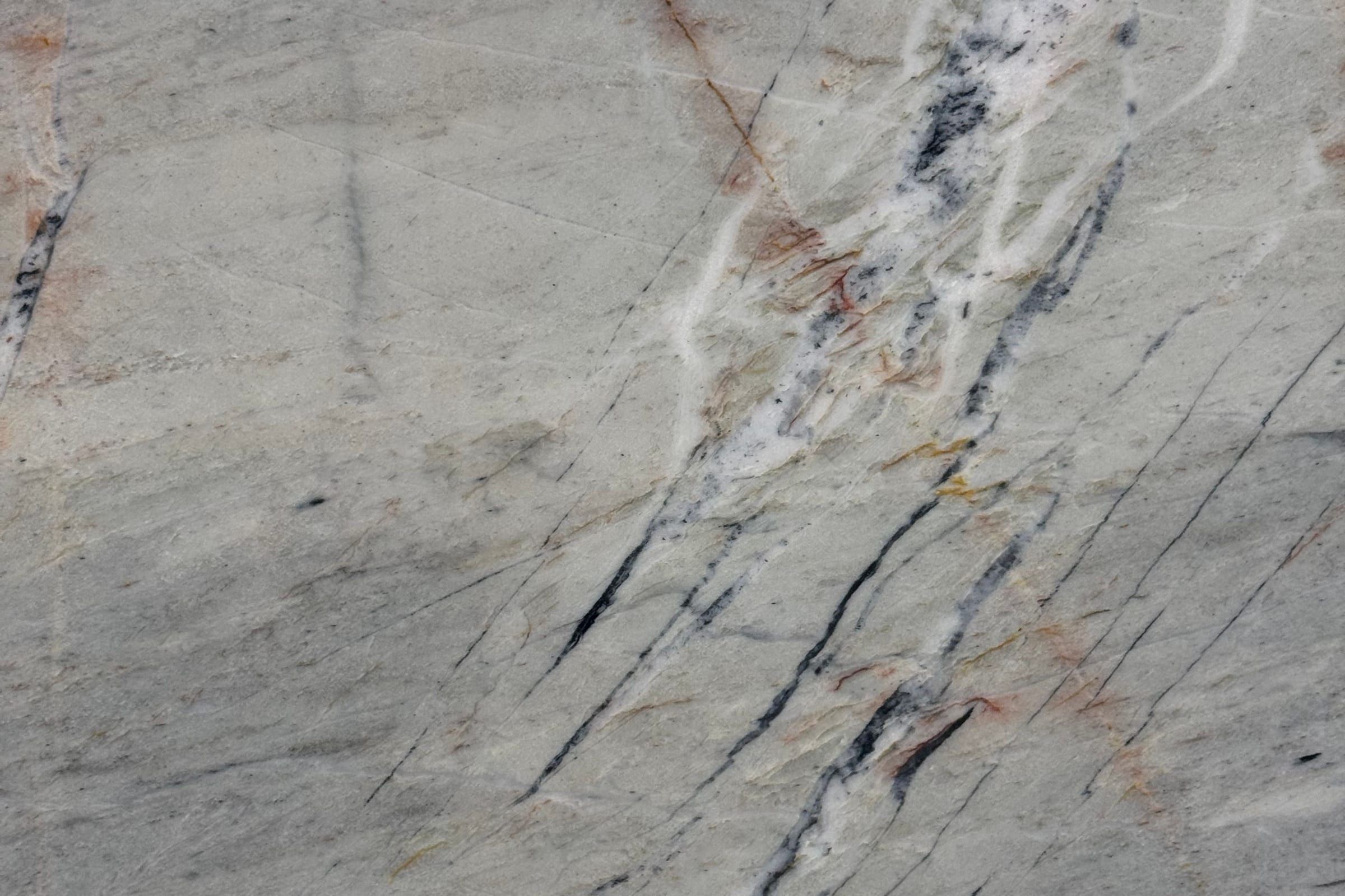 Sage gray-green stone with fine dark fracture lines and thin rust-red and white veins