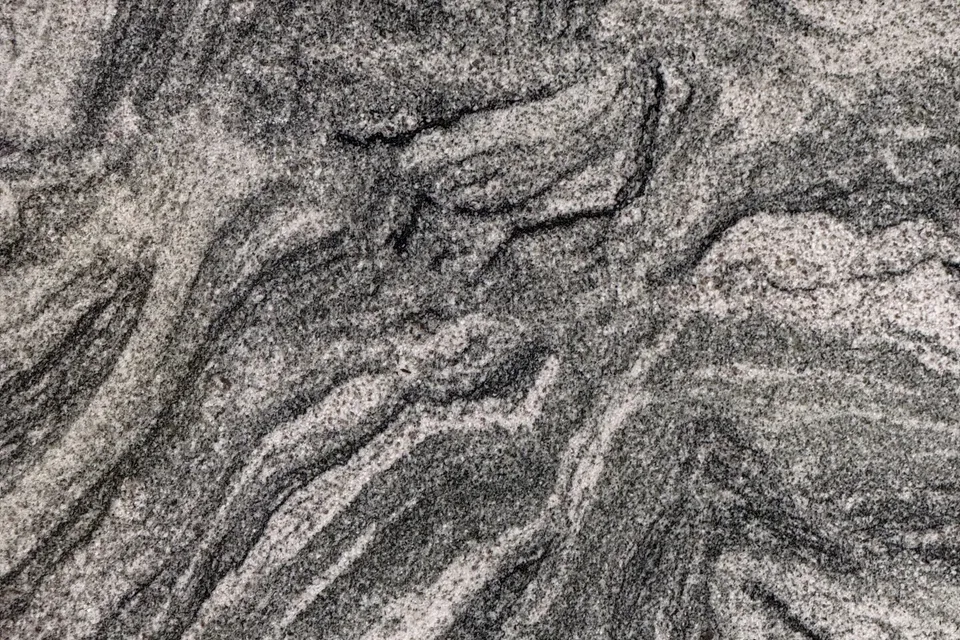 Light gray granular slab with black and white grain and dark swirling bands flowing diagonally
