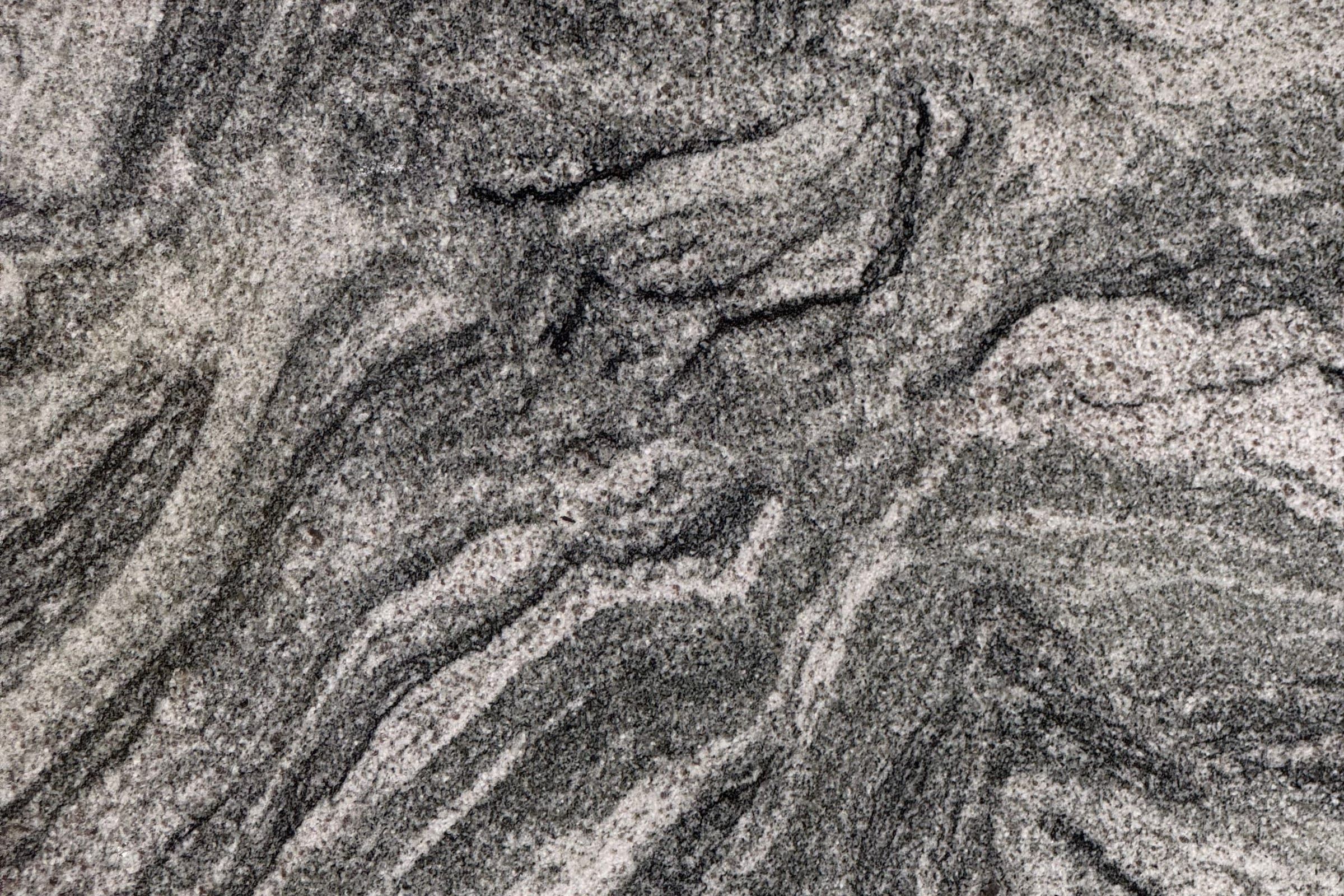 Light gray granular slab with black and white grain and dark swirling bands flowing diagonally