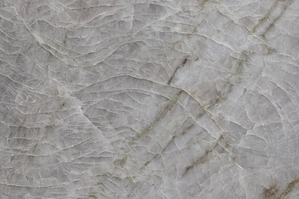 Gray translucent crystalline stone with a network of fine pale fracture lines and tan veins