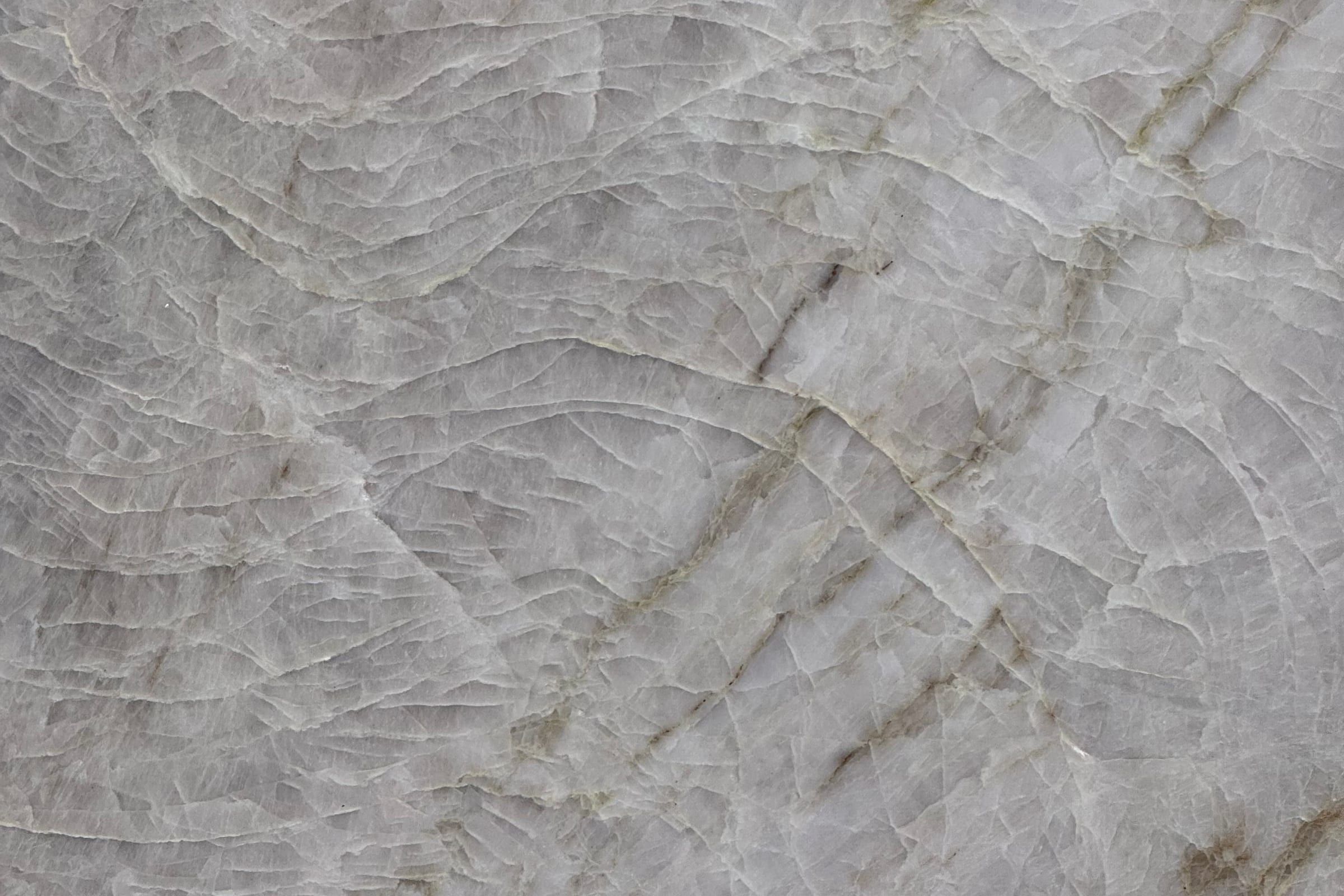 Gray translucent crystalline stone with a network of fine pale fracture lines and tan veins
