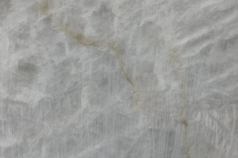 Translucent white stone with soft cloudy patches, a faint gold vein and fine vertical streaks