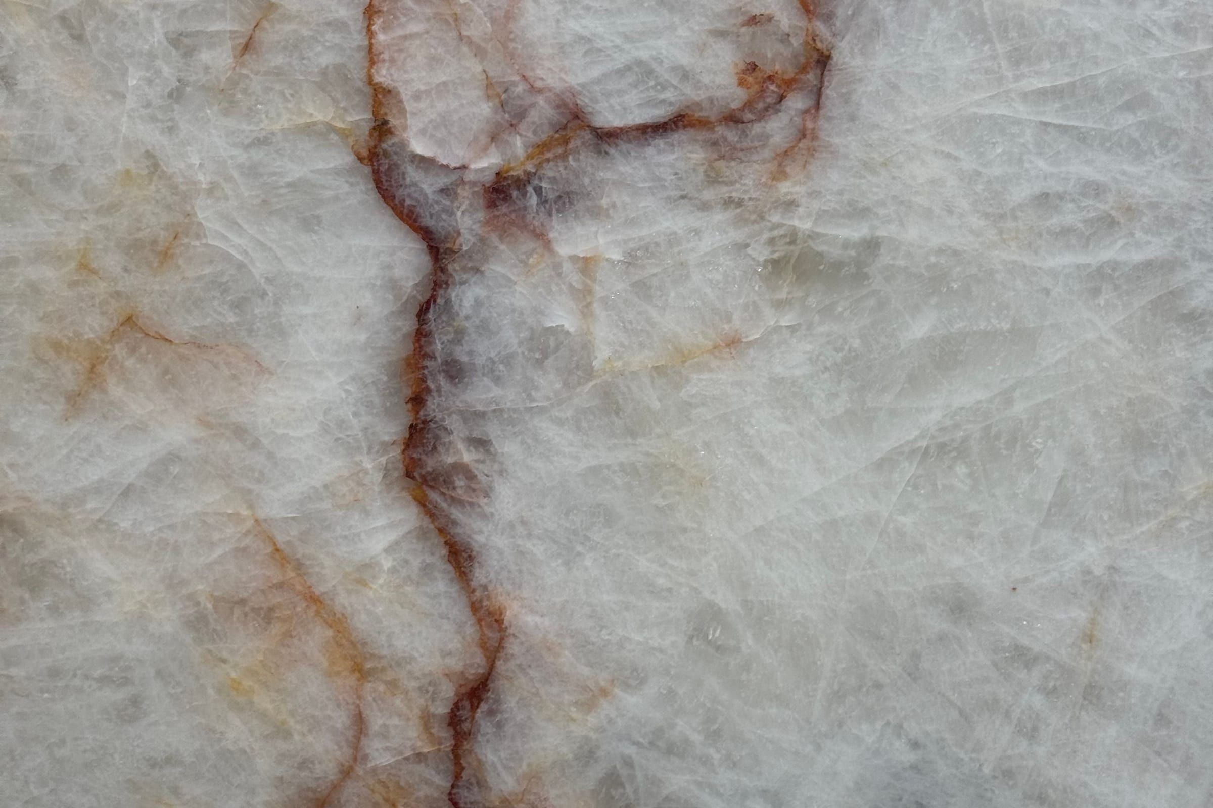 Translucent white crystalline stone with thin red and orange veins branching across it