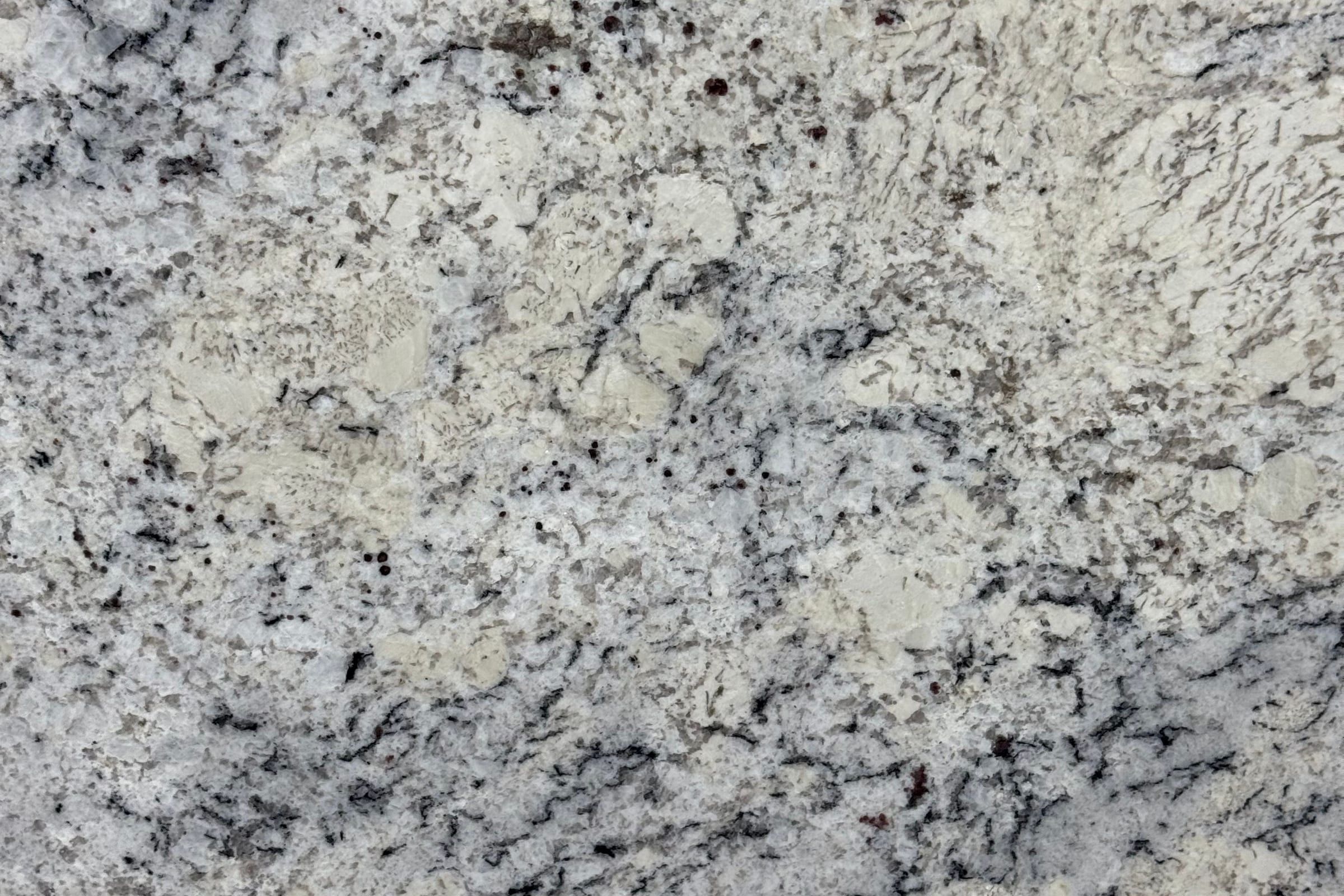 White and gray granite with soft cloudy patches, fine black speckle and a few small red dots